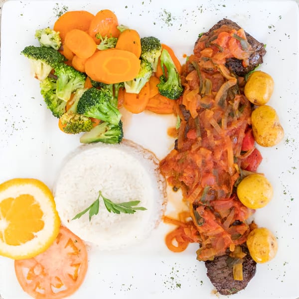 Makondo Restaurant's Colombian dish with steak, tomato sauce, potatoes, rice, broccoli, carrots, orange, and tomato.