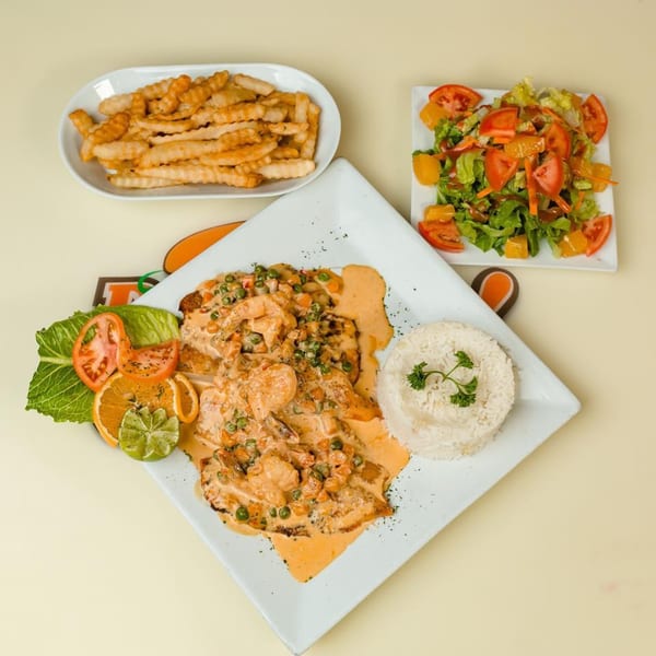 Makondo Restaurant's Colombian dish with shrimp in sauce, rice, fries, and a side salad.