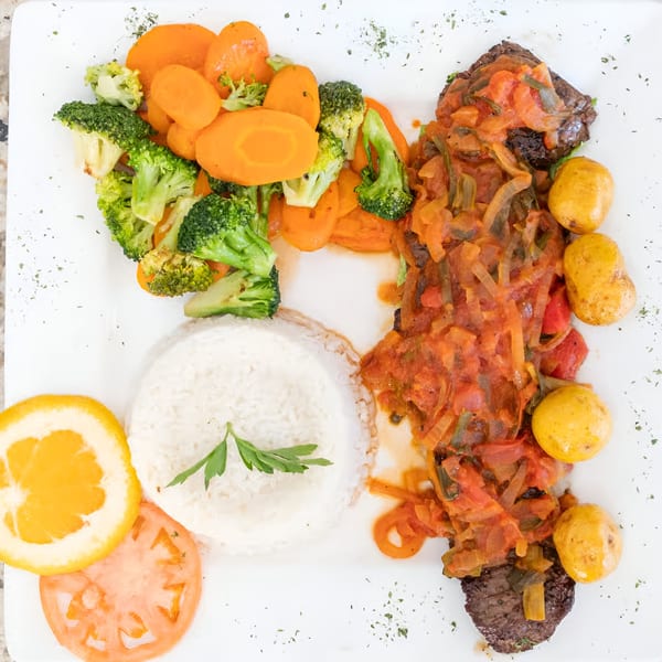 Makondo Restaurant's Colombian dish with steak, tomato sauce, potatoes, rice, broccoli, carrots, orange, and tomato.