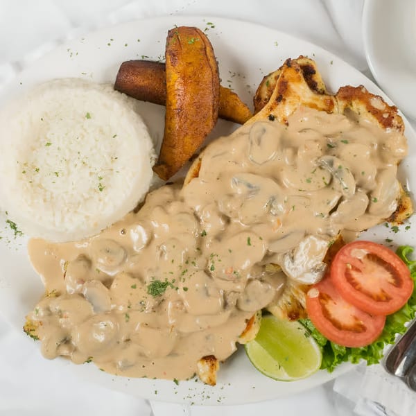Makondo Restaurant's chicken with mushroom sauce, rice, fried plantains, and a side salad.