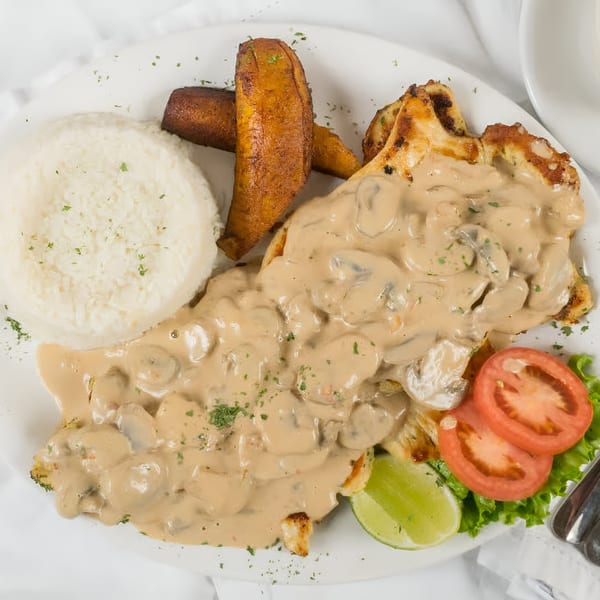 Makondo Restaurant's Colombian chicken in mushroom sauce with rice, plantains, and a side salad.